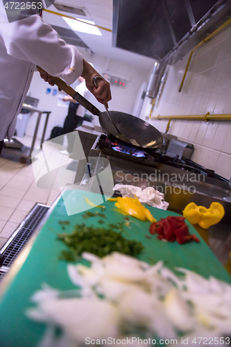 Image of chef preparing food, frying in wok pan