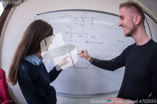 Image of students writing on the white chalkboard