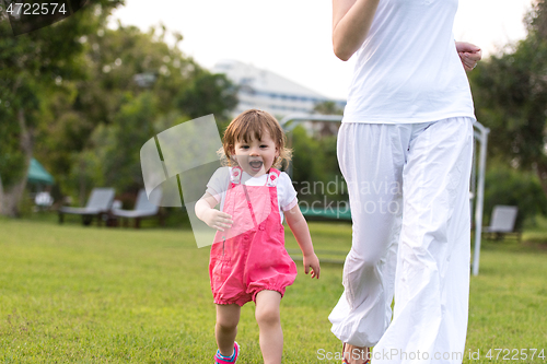 Image of mother and little daughter playing at backyard