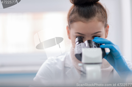 Image of female student scientist looking through a microscope