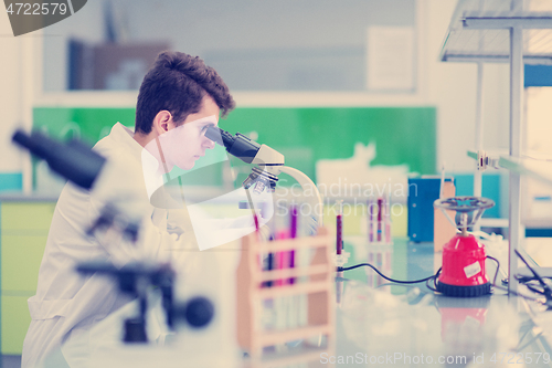 Image of student scientist looking through a microscope