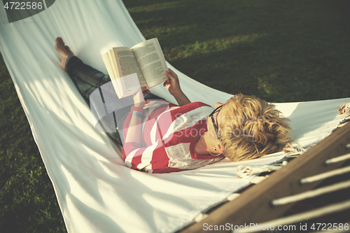 Image of woman reading a book while relaxing on hammock