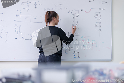 Image of female student writing on board in classroom