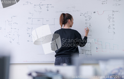 Image of female student writing on board in classroom