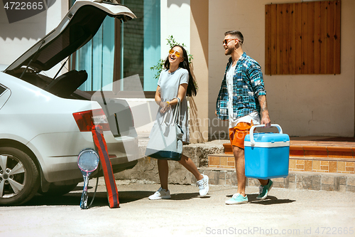 Image of Young couple preparing for vacation trip on the car in sunny day