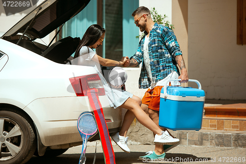 Image of Young couple preparing for vacation trip on the car in sunny day