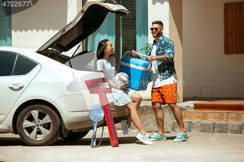 Image of Young couple preparing for vacation trip on the car in sunny day