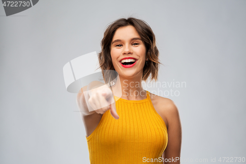 Image of happy smiling young woman pointing to camera