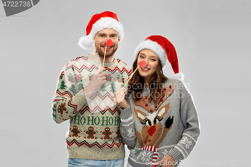 Image of couple with christmas party props in ugly sweaters