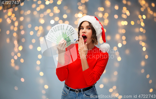 Image of woman in santa hat with money on christmas