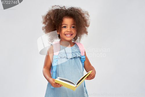 Image of happy little african girl with book and backpack