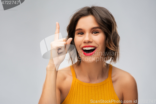 Image of happy smiling young woman pointing finger up