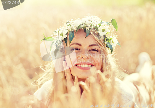 Image of happy woman in wreath of flowers on cereal field