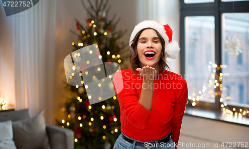 Image of woman in santa hat sending air kiss on christmas