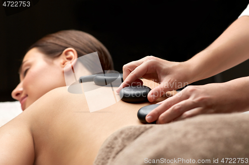 Image of close up of woman having hot stone massage at spa