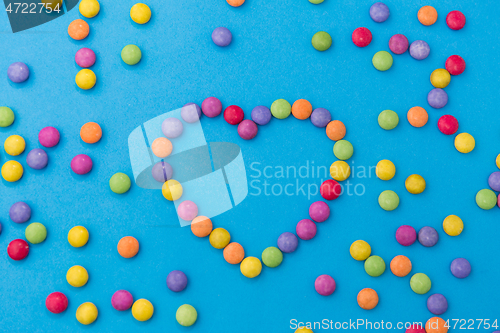 Image of candy drops in shape of heart on blue background