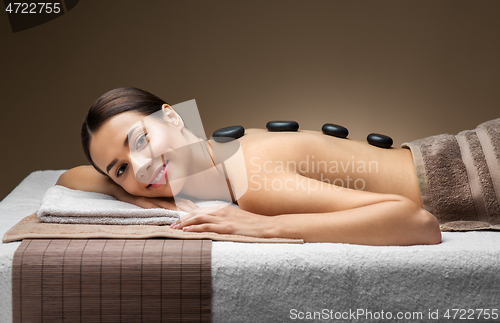 Image of smiling woman having hot stone massage at spa