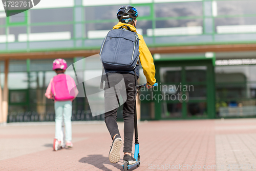 Image of school children with backpacks riding scooters