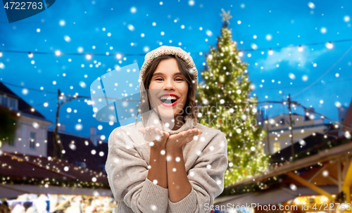 Image of woman in hat sending air kiss at christmas market