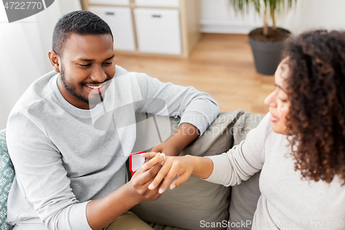 Image of african american man giving woman engagement ring