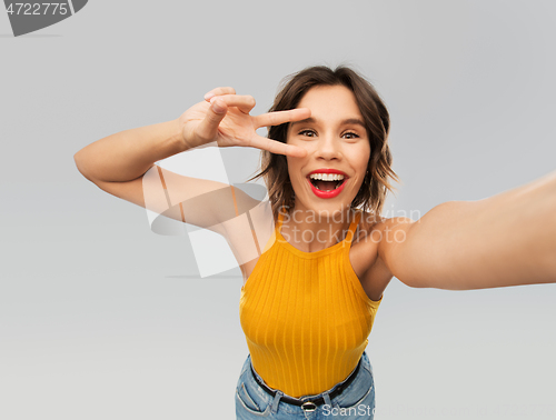 Image of happy woman taking selfie and showing peace sign