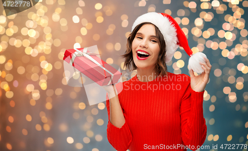 Image of happy young woman in santa hat with red gift box