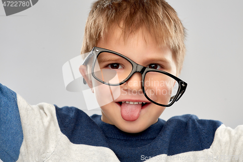 Image of portrait of little boy in glasses showing tongue