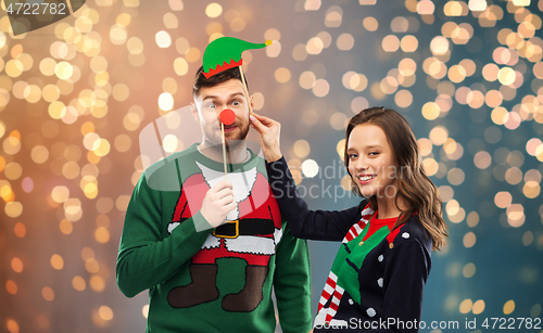 Image of couple with christmas party props in ugly sweaters