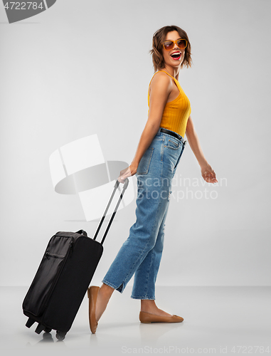 Image of happy young woman in sunglasses with travel bag