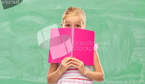 Image of little girl hiding over book at school