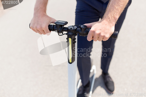 Image of young businessman riding electric scooter outdoors