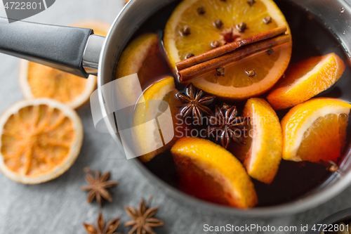 Image of pot with hot mulled wine, orange slices and spices