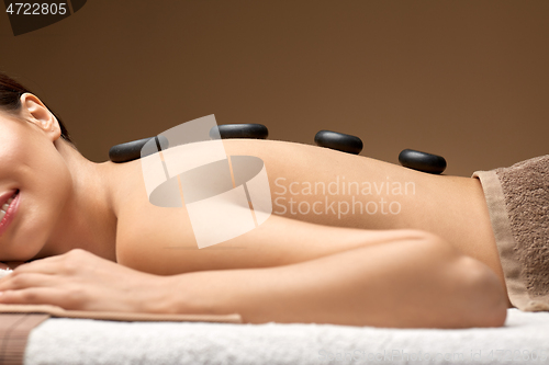 Image of smiling woman having hot stone massage at spa