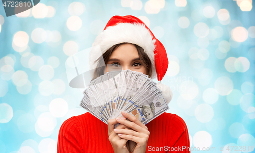 Image of happy woman in santa hat with money on christmas