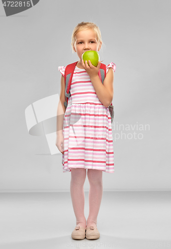 Image of little school girl eating green apple