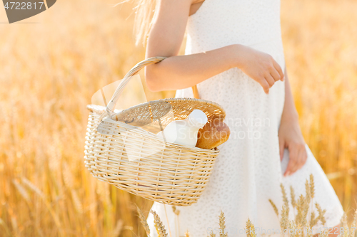 Image of girl with bread and milk in basket on cereal field