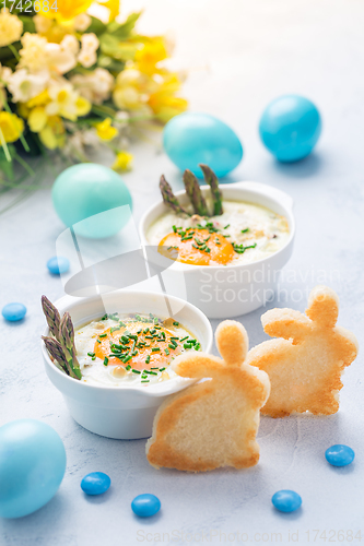 Image of Shirred eggs (Oeuf cocotte) or baked eggs with green asparagus with Easter bunny and eggs