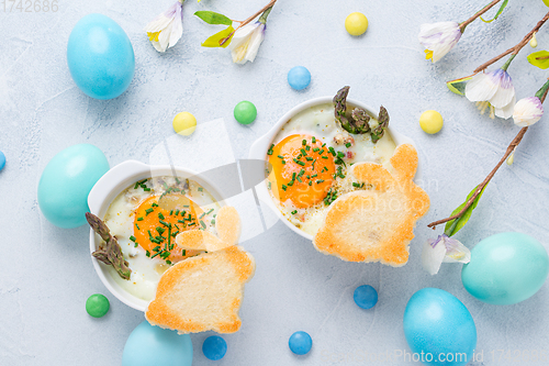 Image of Shirred eggs (Oeuf cocotte) or baked eggs with green asparagus with Easter bunny and eggs