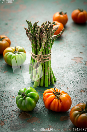 Image of Assortment of organic tomatoes and green asparagus on old kitchen table