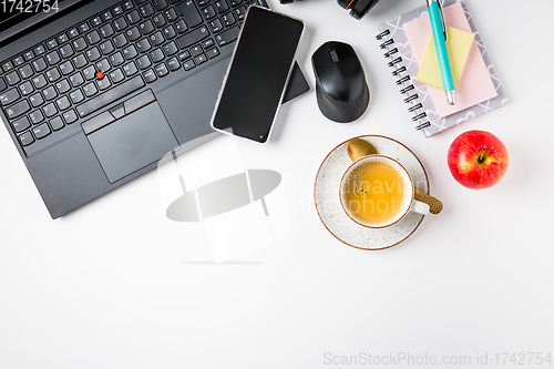 Image of Working place and office desk with coffee, apple, laptop, headset and smarthpone