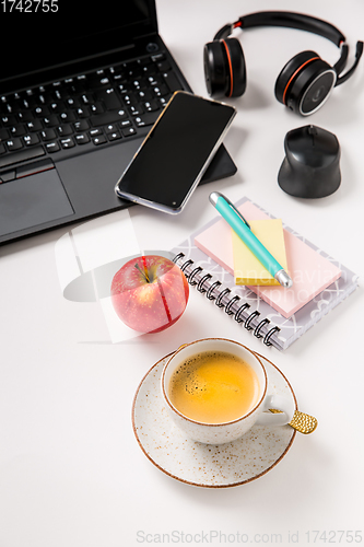 Image of Working place and office desk with coffee, apple, laptop, headset and smarthpone