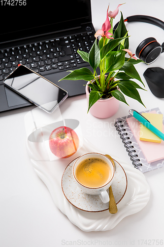 Image of Working place and office desk with coffee, apple, laptop, headset and smarthpone