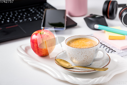 Image of Working place and office desk with coffee, apple, laptop, headset and smarthpone