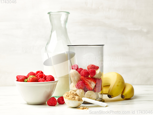 Image of fresh banana pieces and red berries in plastic transparent blend