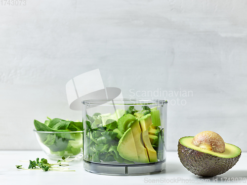 Image of avocado, celery and spinach in plastic transparent blender conta