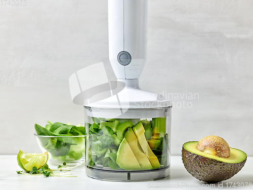 Image of avocado, celery and spinach in plastic transparent blender conta