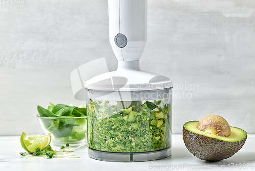 Image of avocado, celery and spinach in plastic transparent blender conta