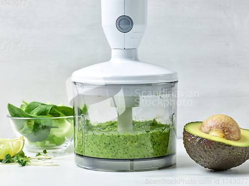 Image of avocado, celery and spinach in plastic transparent blender conta