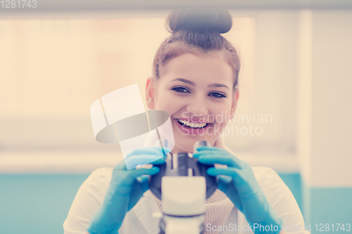 Image of female student scientist looking through a microscope