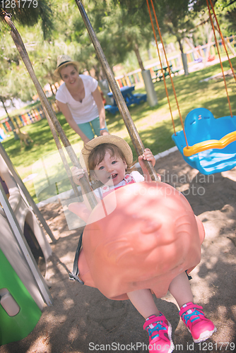 Image of mother and daughter swinging in the park